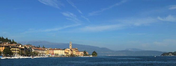 Trip Kärnten beliebte Urlaubsziele am Gardasee -  Mit einer Fläche von 370 km² ist der Gardasee der größte See Italiens. Es liegt am Fuße der Alpen und erstreckt sich über drei Staaten: Lombardei, Venetien und Trentino. Die maximale Tiefe des Sees beträgt 346 m, er hat eine längliche Form und sein nördliches Ende ist sehr schmal. Dort ist der See von den Bergen der Gruppo di Baldo umgeben. Du trittst aus deinem gemütlichen Hotelzimmer und es begrüßt dich die warme italienische Sonne. Du blickst auf den atemberaubenden Gardasee, der in zahlreichen Blautönen schimmert - von tiefem Dunkelblau bis zu funkelndem Türkis. Majestätische Berge umgeben dich, während die Brise sanft deine Haut streichelt und der Duft von blühenden Zitronenbäumen deine Nase kitzelt. Du schlenderst die malerischen, engen Gassen entlang, vorbei an farbenfrohen, blumengeschmückten Häusern. Vereinzelt unterbricht das fröhliche Lachen der Einheimischen die friedvolle Stille. Du fühlst dich wie in einem Traum, der nicht enden will. Jeder Schritt führt dich zu neuen Entdeckungen und Abenteuern. Du probierst die köstliche italienische Küche mit ihren frischen Zutaten und verführerischen Aromen. Die Sonne geht langsam unter und taucht den Himmel in ein leuchtendes Orange-rot - ein spektakulärer Anblick.